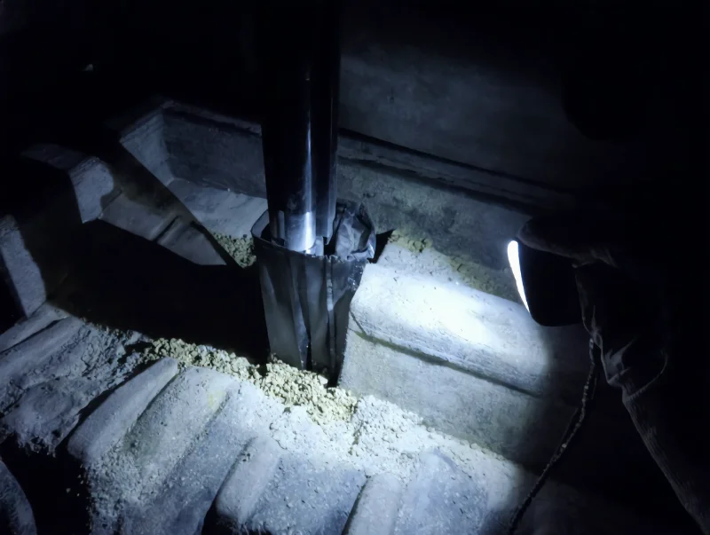 Intérieur de cabine basculante où le gravier atteint le pivot du levier de vitesses à travers un coffre fendu