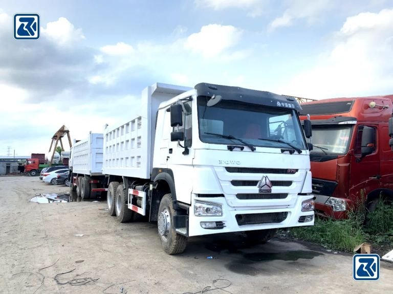 Des camions bennes HOWO neufs et reconditionnés alignés, illustrant les niveaux d'état qui font varier le prix d'un camion benne HOWO